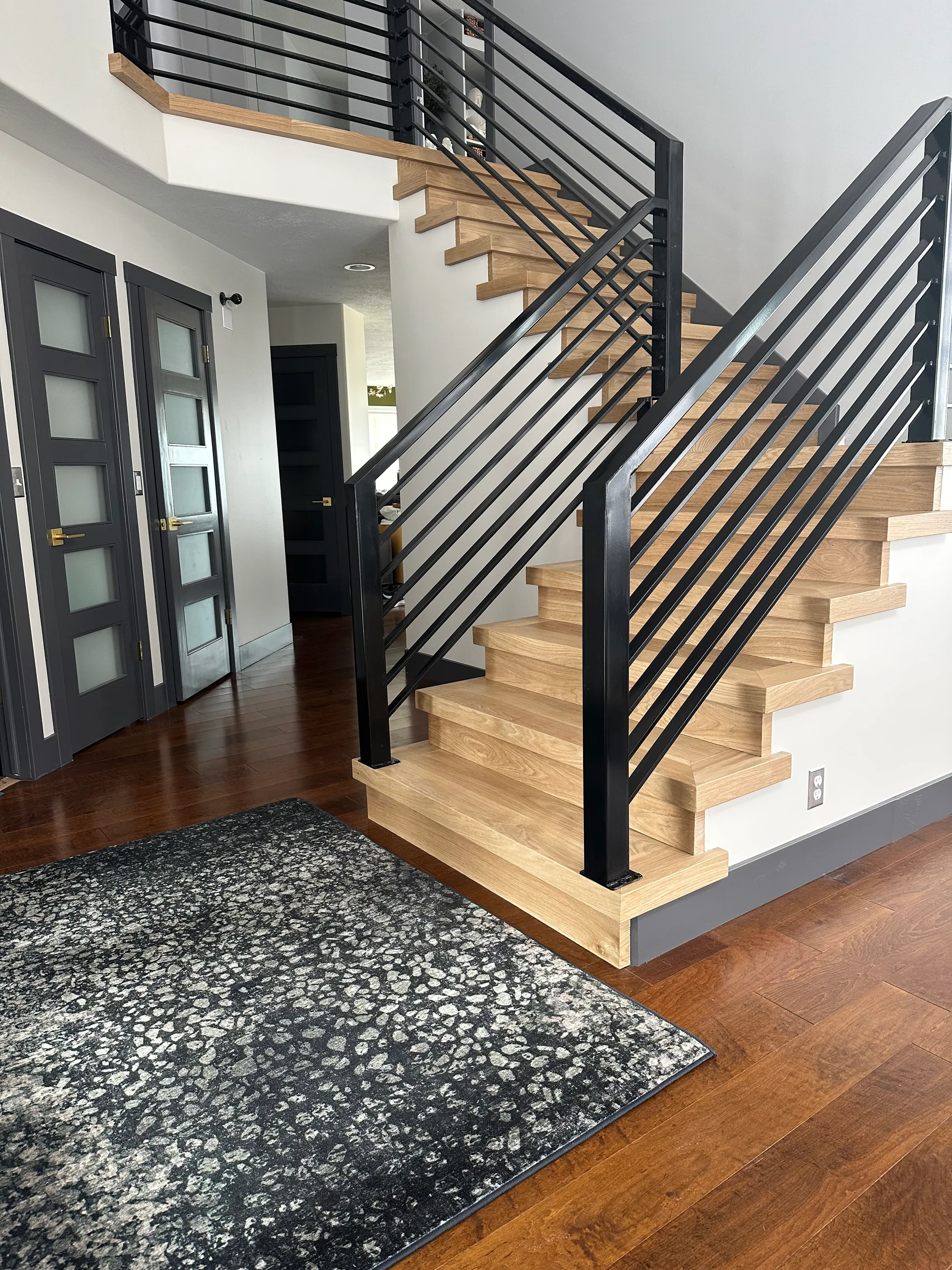 Custom white oak staircase with squared treads and risers in contemporary interior with metal railings