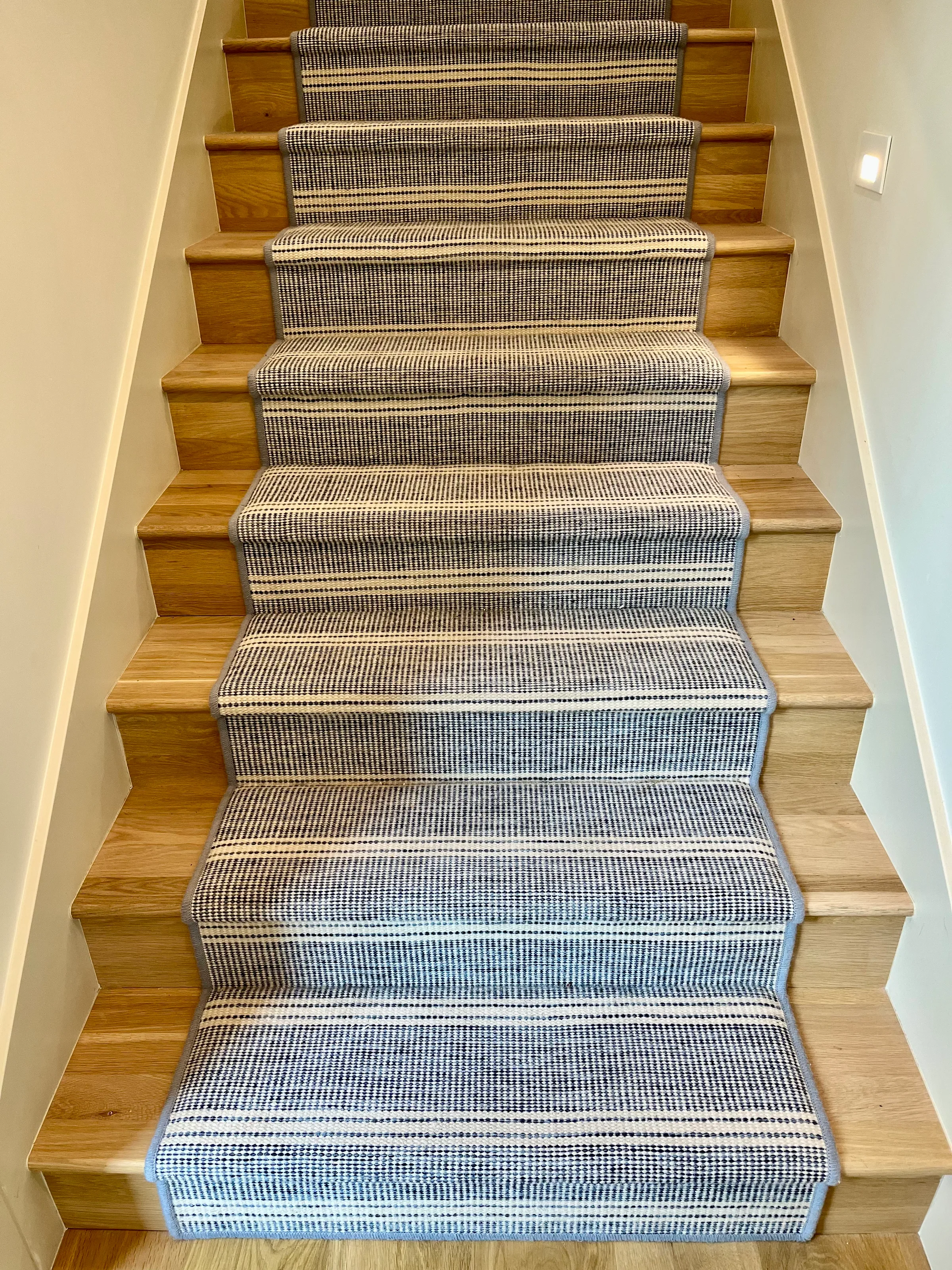 White oak staircase with standard round tread profile and natural wood risers in bright stairwell