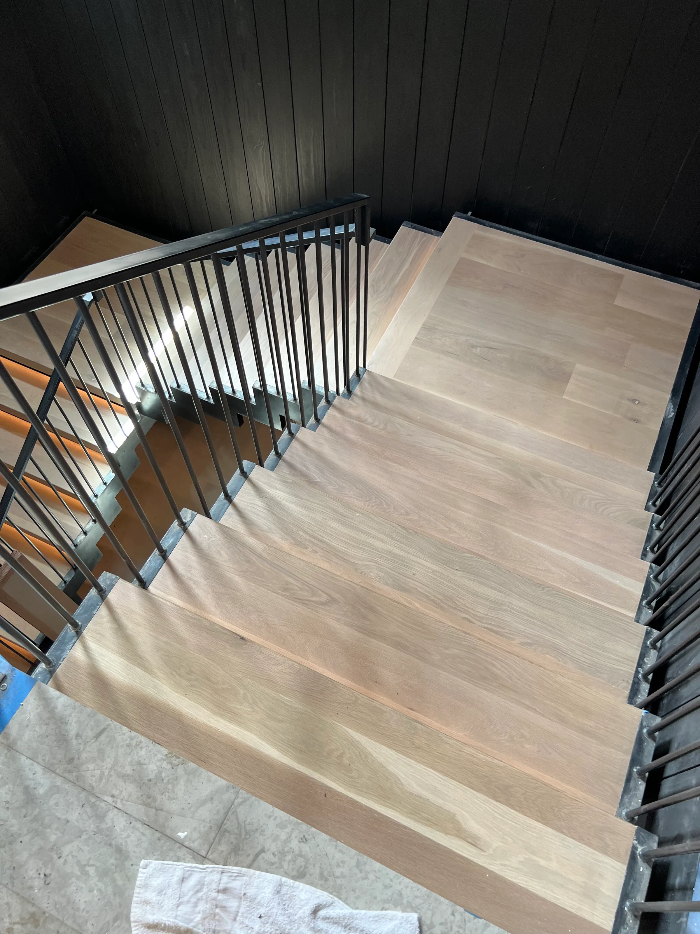 Custom white oak suspended staircase with cantilevered treads and contemporary geometric metal railing
