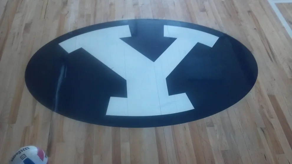 Hardwood sport floor with navy painted lines and detailed custom logo featuring a cougar figure and team emblem inlay