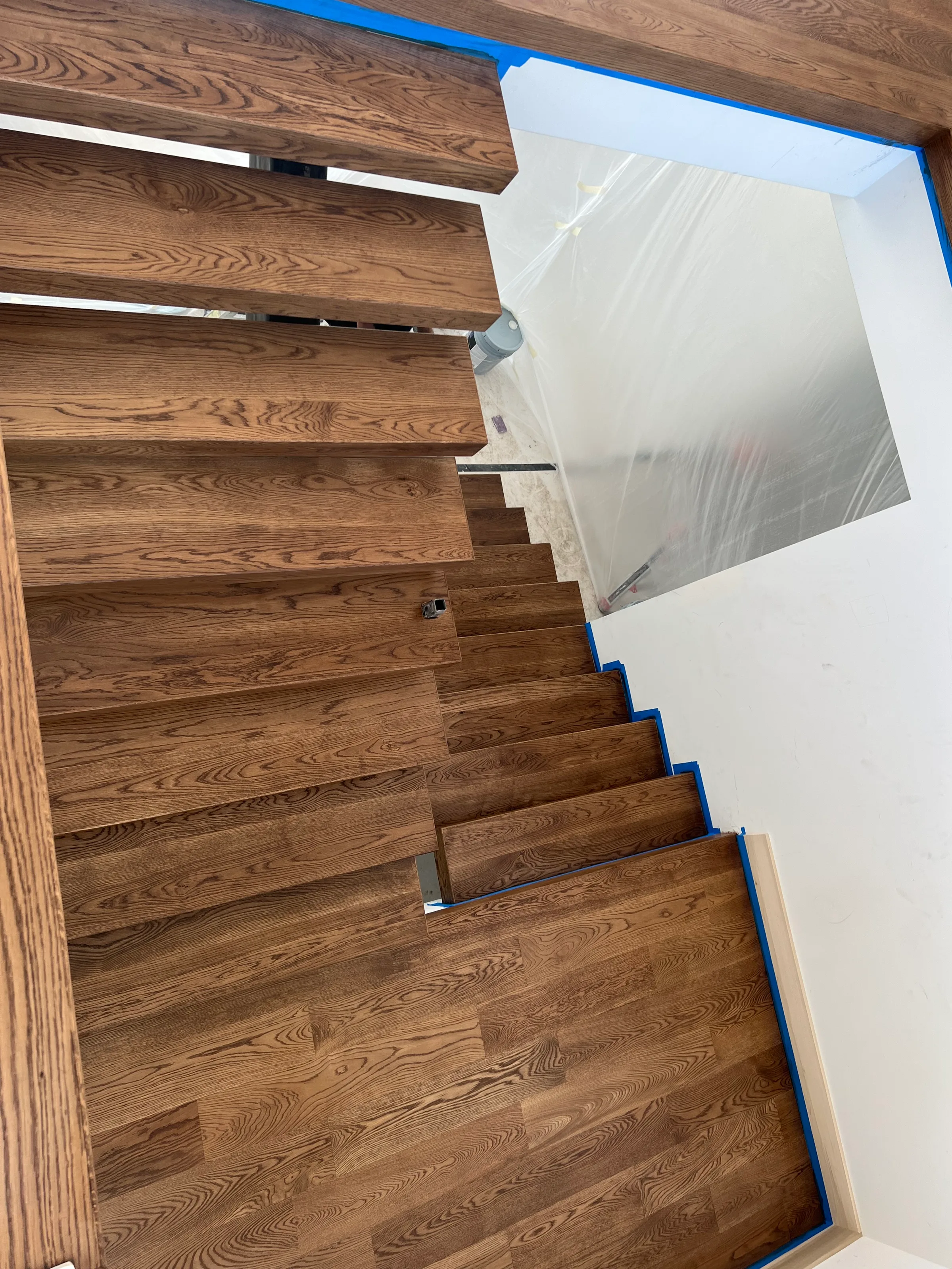 White oak floating stair treads with suspended design and sleek modern metal railings in minimalist staircase