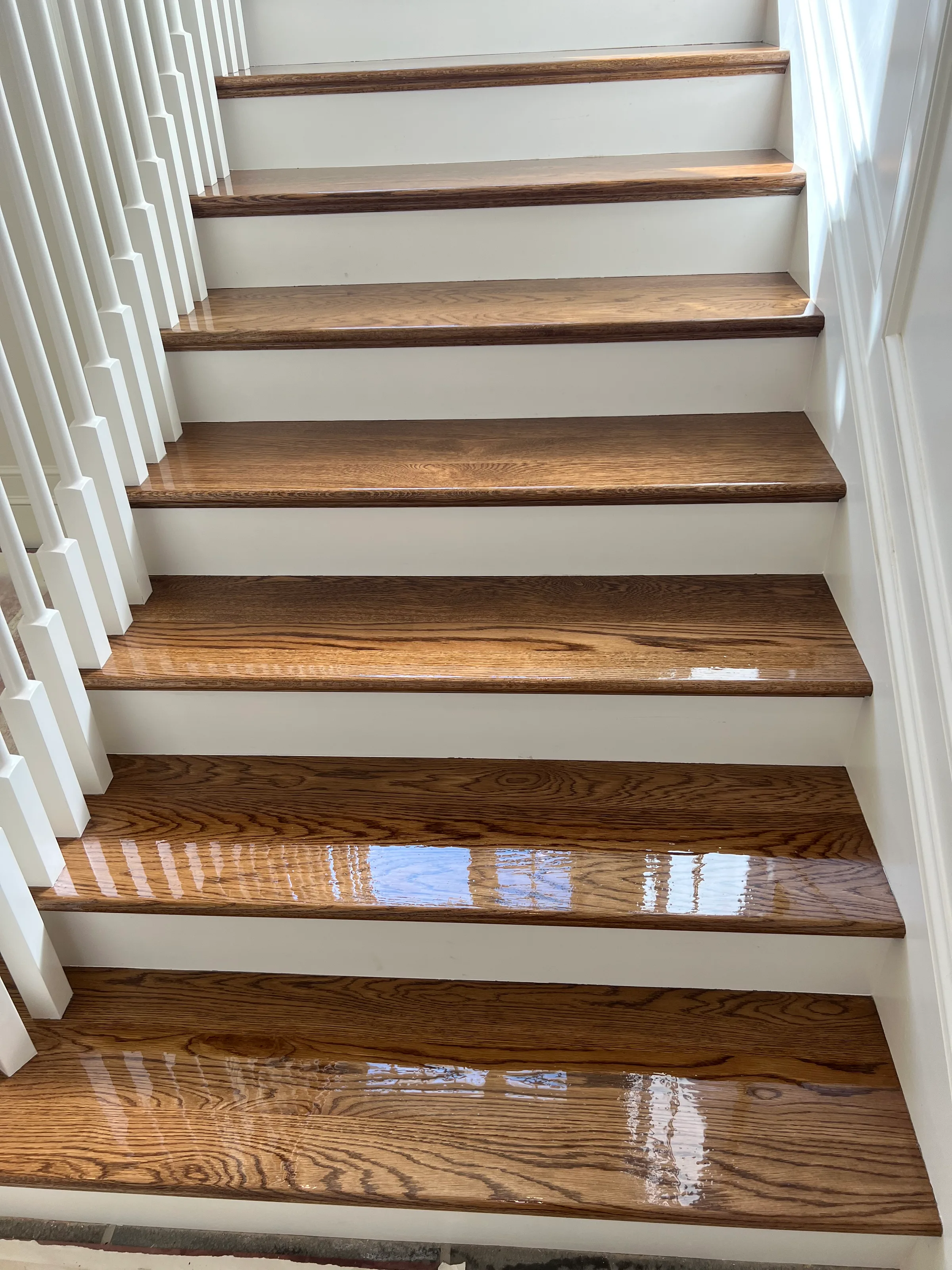 Refinished oak stair treads with round profiles and paint grade risers showing renewed wood finish