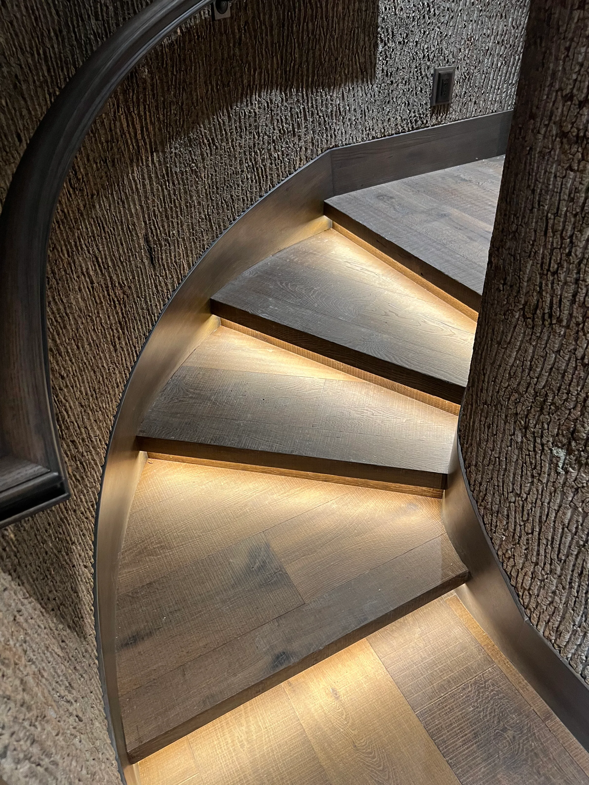 Pre-finished wood staircase treads with factory finish in light natural tone on curved contemporary stair installation