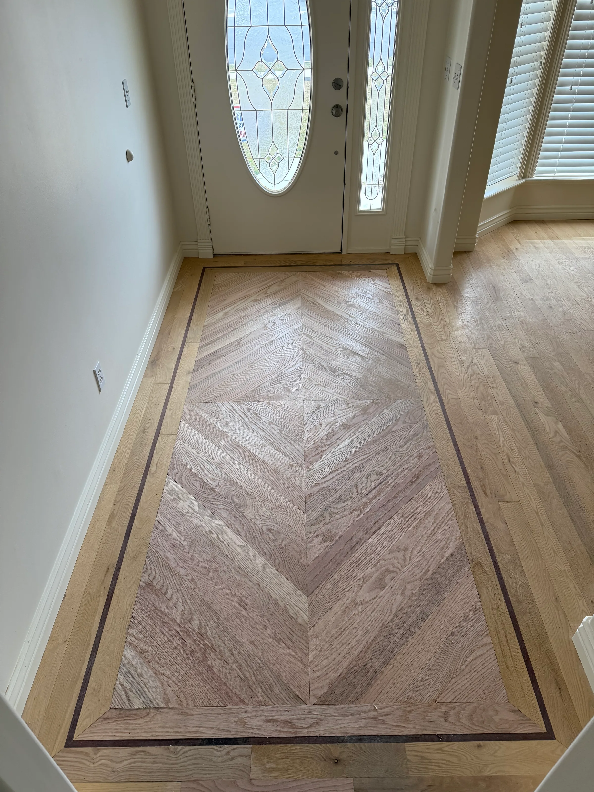 Red oak hardwood flooring with geometric pattern layout showing natural color and grain in room interior