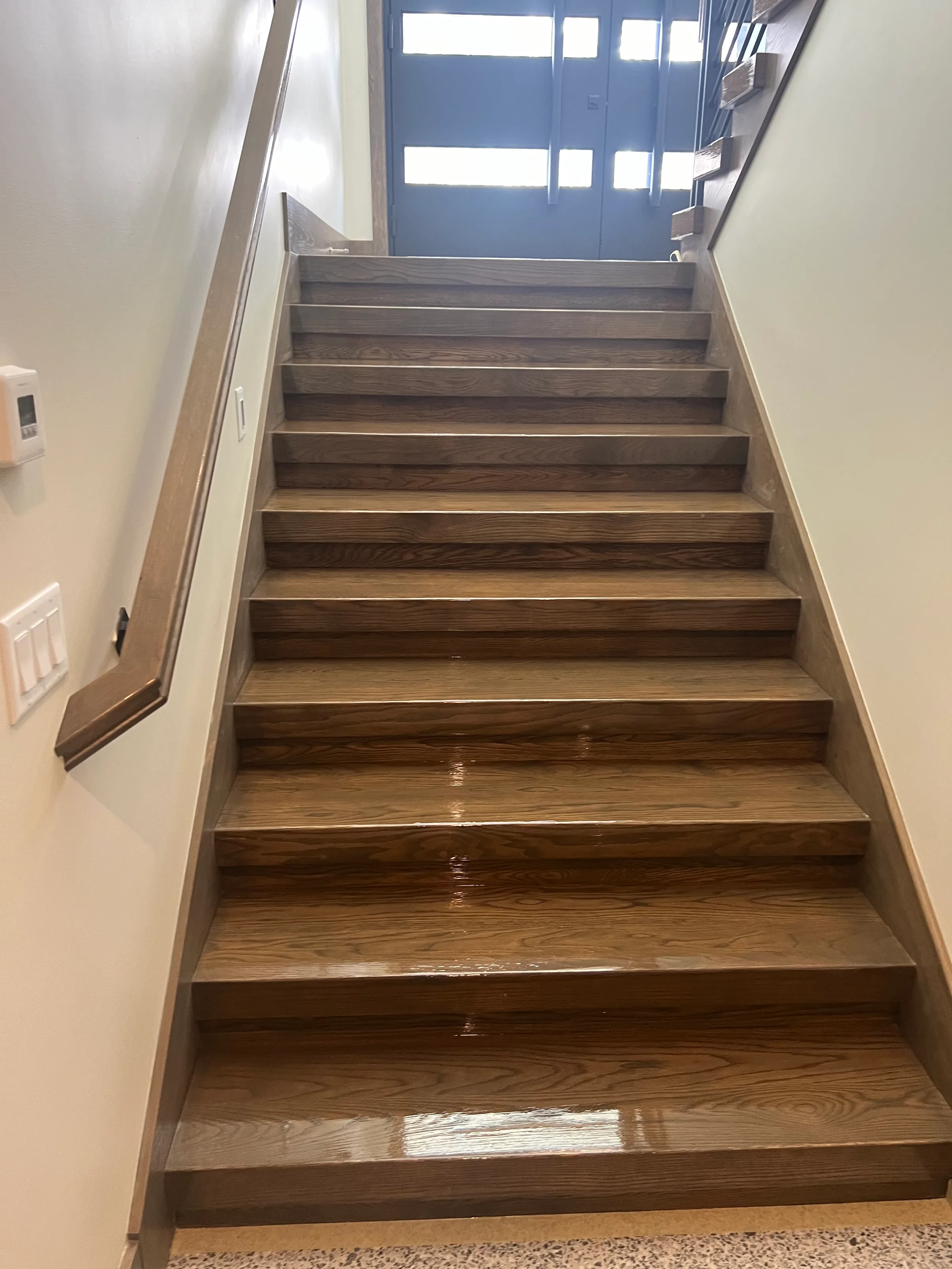 Custom white oak staircase with squared treads and risers in neutral tone wood with metal support structure