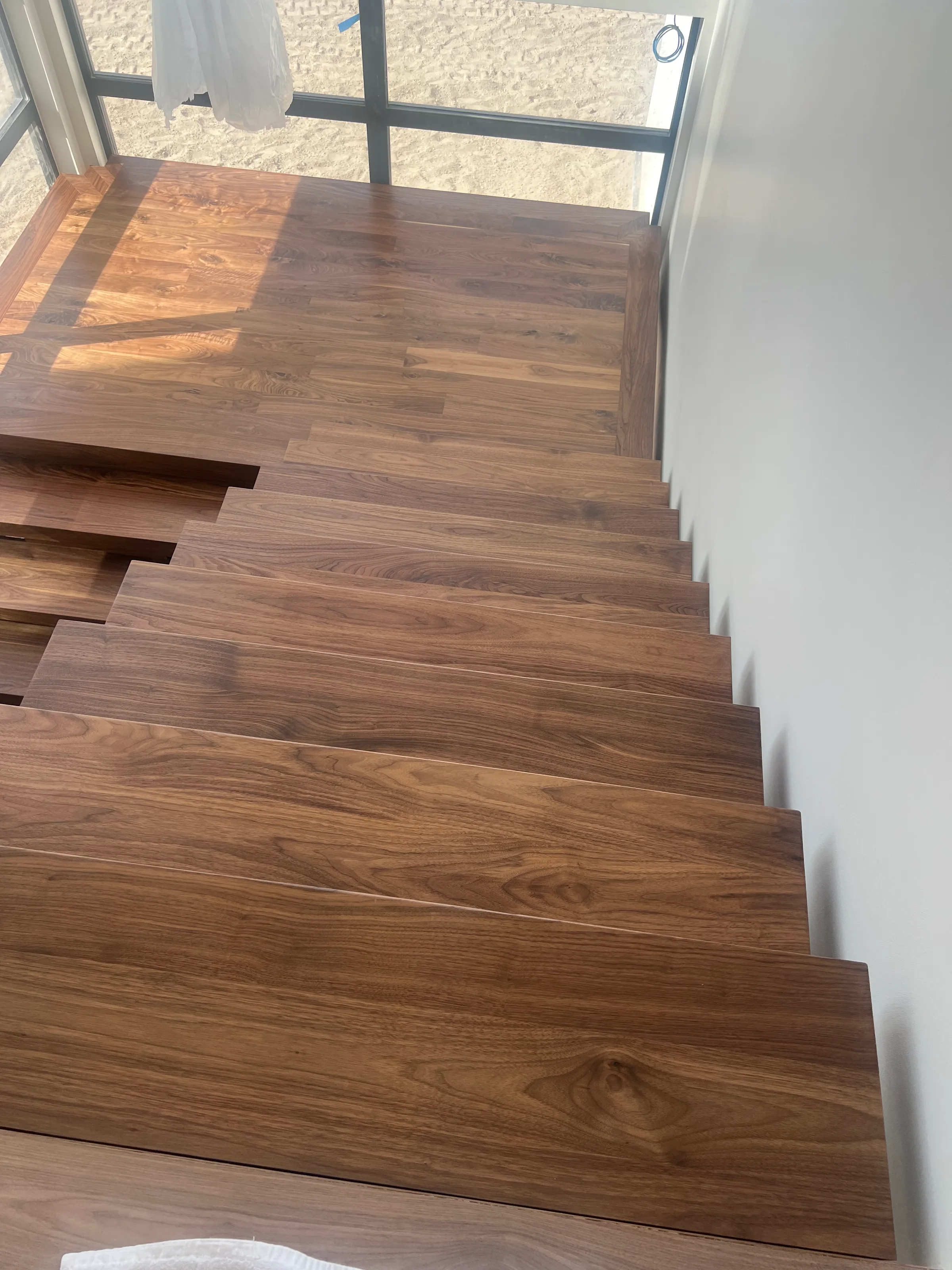 Custom walnut wood staircase with floating suspended treads and black metal railings in modern space