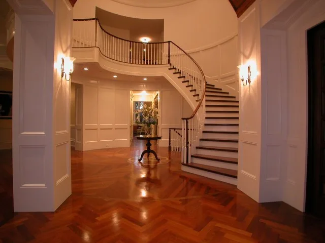 Cherry wood flooring with geometric inlay pattern and herringbone field in a bright foyer entry