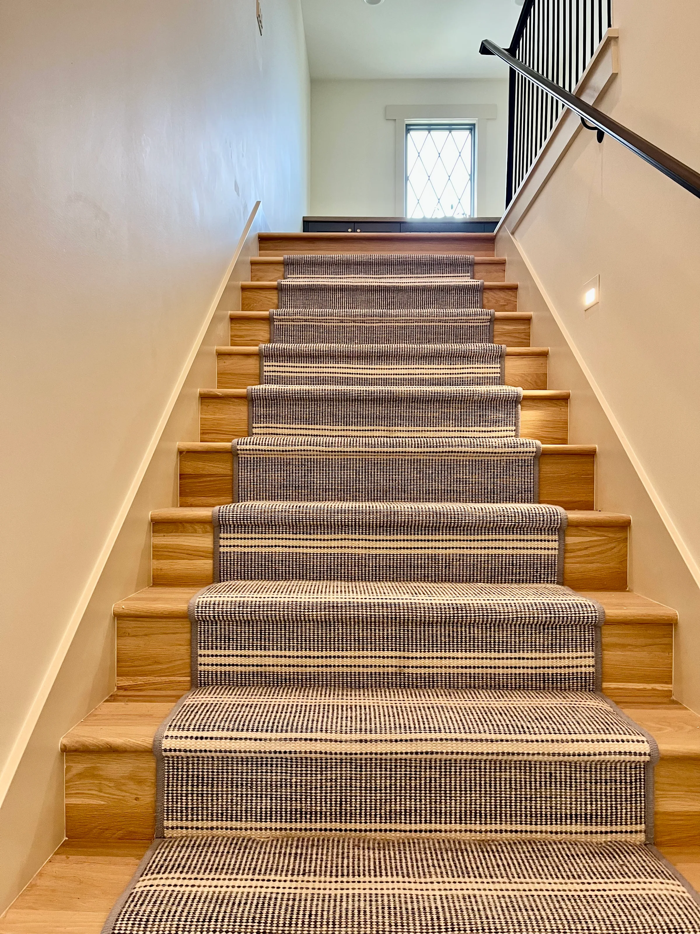 Custom white oak stairs with standard round treads and visible natural grain in residential stairwell